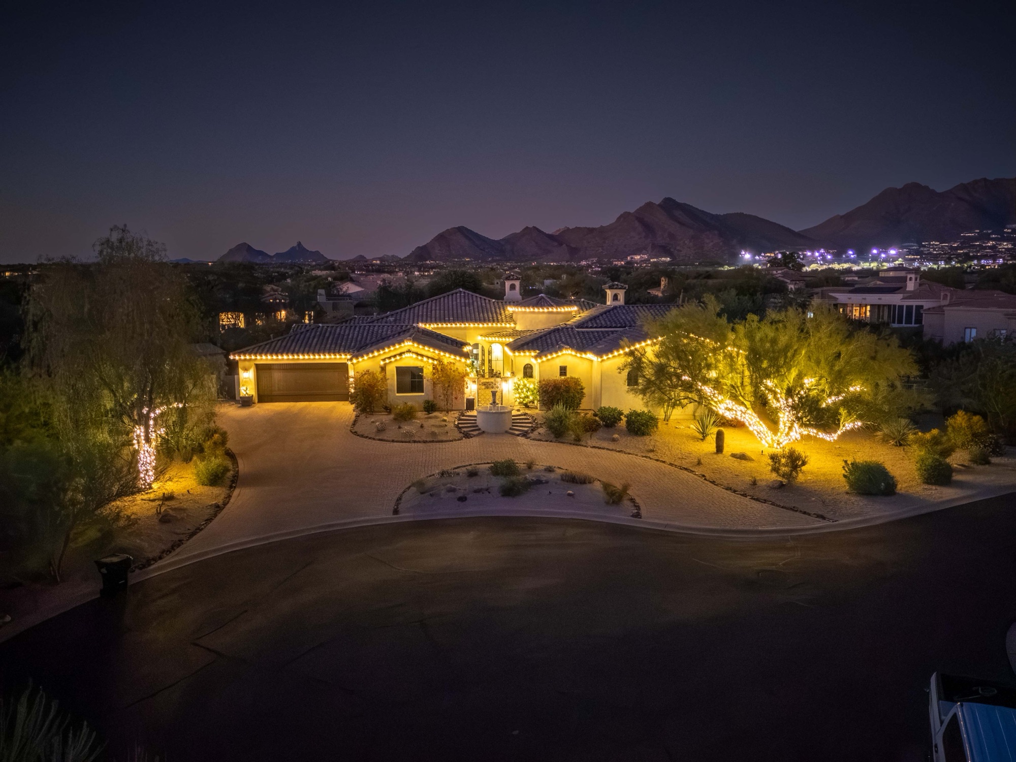 Aerial dusk view of a lit estate against the McDowell Mountains